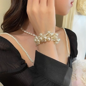 Elegant beaded pearl bracelet featuring a white flower charm worn on a model's wrist