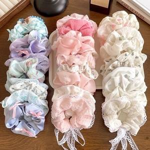 Set of 21 floral lace scrunchies in pastel colors arranged on a wooden surface