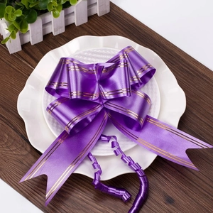 Detail of purple satin pull bow ribbon with gold stripes and curled ends for decor