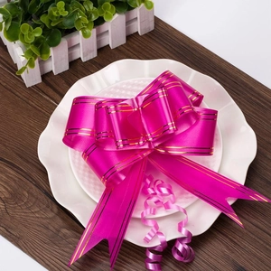 Detail of rose red wedding pull bow with gold edges on a decorative white plate