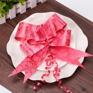 Detail view of a large red wedding bow with embossed rose patterns on a white decorative plate