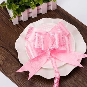 Close-up of pink decorative gift bow with rose patterns on elegant white ceramic plates