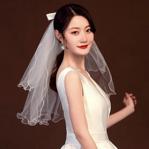 Short two-layer white bridal veil with bow ribbon detail on model with brown background