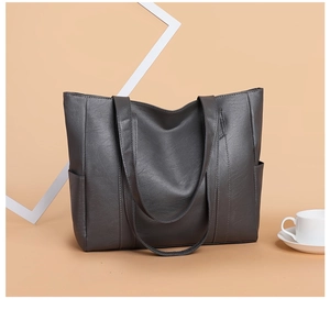 Detail view of large grey PU leather tote bag with side pockets and top handles