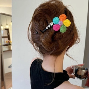 Detail of colorful knitted flower hair clip with heart rhinestones on wavy brown hair