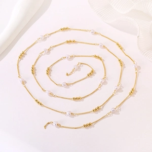 Detail of a long gold chain with white heart beads and small gold spheres in a spiral layout