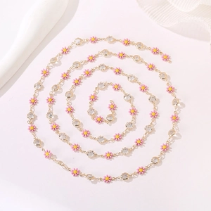 Close-up of pink daisy charm necklace with gold chain and sparkling rhinestones