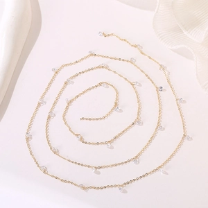 Macro detail of a gold thin chain necklace with transparent teardrop zircon pendants