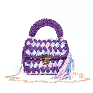 Close-up of handmade woven handbag with gold metal handles and mixed tricolor fabric