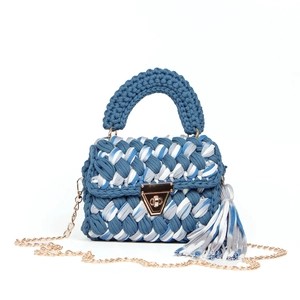Detailed view of woven handbag featuring blue stripes, gold metal lock and chain strap