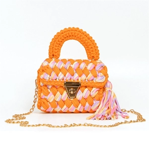 Detail of handmade orange woven handbag with colorful fringe and gold metal clasp