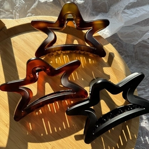Star-shaped hair claw clips in amber, brown, and black colors on a wooden tray
