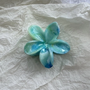 Detailed top view of blue marble texture flower hair claw clip on soft paper