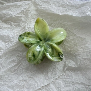 Detailed top view of a marble texture flower hair claw clip with green and white patterns