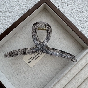 Detailed top view of a large transparent claw clip with black lace mesh and gold spring