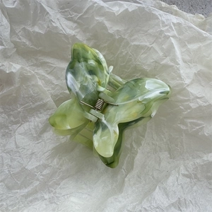Detailed close-up of butterfly hair claw clip with green and white marble pattern texture
