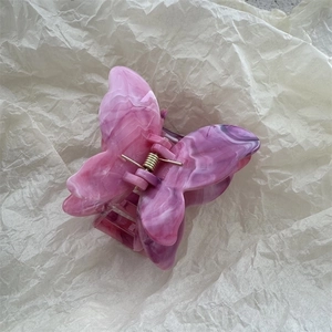 Close-up of pink and purple marble pattern butterfly hair claw with golden metal spring