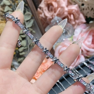 Detail showing silver X-link bracelet with pink and blue gemstones and 18K gold plating