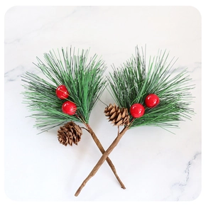 Detail of artificial Christmas pine branches with red berries and pine cones on marble