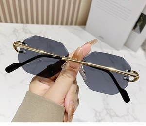 Close-up of frameless sunglasses featuring gold metal temples and grey lenses