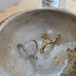 Abstract knotted 925 silver rings in gold and silver finish on a ceramic bowl