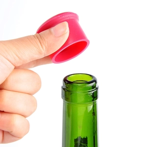 Food-grade red silicone beer bottle cap being placed on a green glass bottle neck