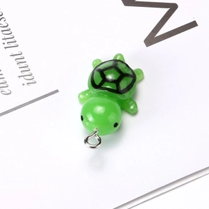 Detailed close-up of a green resin turtle pendant with realistic shell patterns and metal ring