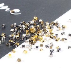Sortierte Kupfer-Quetschperlen und Röhrchen für DIY-Schmuck auf schwarz-weißem Hintergrund