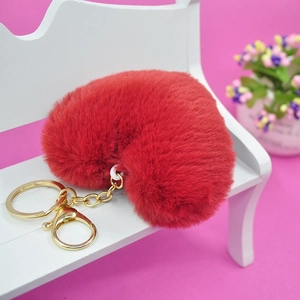 Red plush heart keychain with gold metal ring on a miniature white bench setup