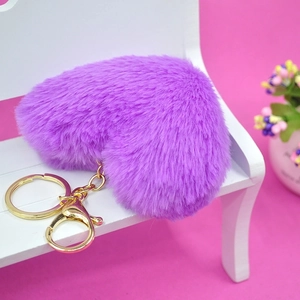 Detailed macro view of a purple plush heart keychain on a small white wooden bench