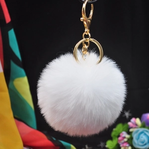 Close-up of soft white faux rabbit fur pom pom keychain with gold metal ring and clasp