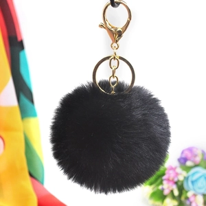 Detail of 8cm black faux rabbit fur keychain with golden metal clasp on white background