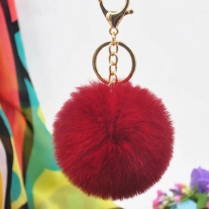 Detailed shot of dark red faux rabbit fur pom pom keychain with gold lobster clasp