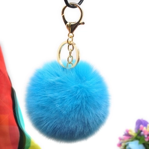Detailed view of fluffy blue faux rabbit fur pompom keychain with golden metal ring
