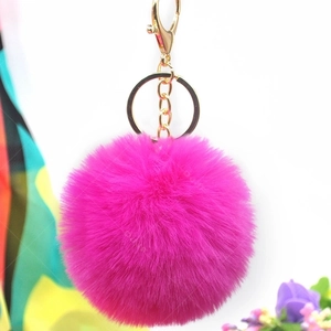 Detail view of a soft pink faux rabbit fur pompom with a gold metal keychain and lobster clasp