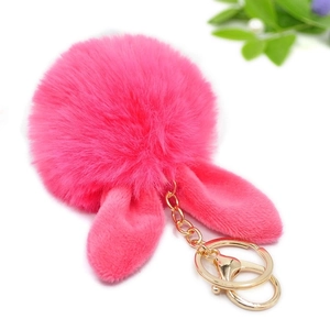 Close-up of pink faux fur pompom keychain with rabbit ears and golden clasp for bags