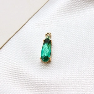 Detail of green teardrop faceted glass pendant with gold-plated claw setting and ring