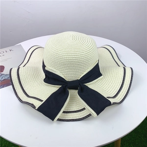 Women's wide brim straw sun hat in beige with black ribbon bow and striped edge