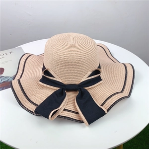 Women straw sun hat in beige with wide wavy brim and large black bow decoration