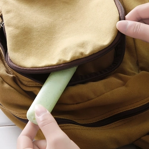 Eco-friendly wheat straw toothbrush case in light green stored in a brown backpack pocket