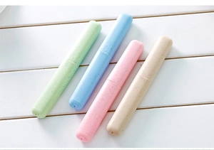 Macro detail of portable wheat straw toothbrush cases in four pastel colors on wood