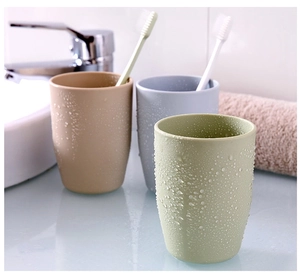 Three minimalist bathroom tumblers in beige, gray and green with fresh water droplets