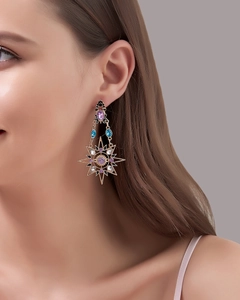 Detail of baroque gold earrings featuring starburst motifs and colorful gemstones