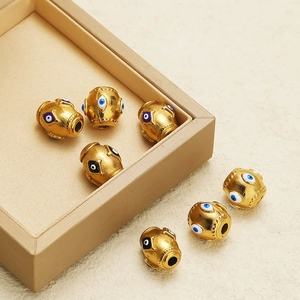 Golden stainless steel evil eye spacer beads for DIY jewelry making on white background