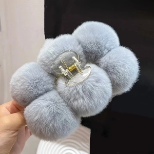 Detailed close-up of a large grey-blue plush hair claw clip with soft faux rabbit fur balls
