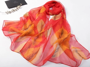 Macro detail of red silk scarf with orange leaf pattern and fine hemmed edges