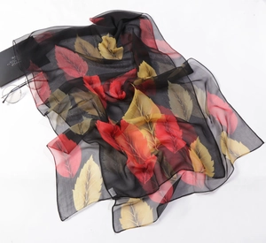 Detail of a black chiffon shawl with colorful leaves and 100% polyester fabric tag