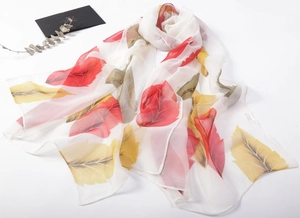 Close-up of lightweight chiffon scarf featuring vibrant red and yellow feather patterns