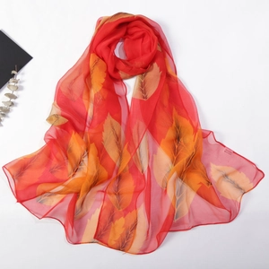Detail of long red chiffon scarf with autumn leaf print and care label information