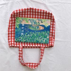 Top view of red gingham cotton tote bag with a decorative book on white fabric